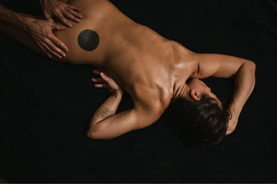 A woman receiving a tantra massage lying on her stomach